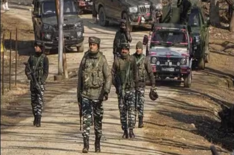 Group of soldiers patrolling a rural road with military vehicles in the background.